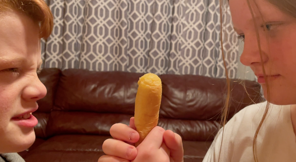 two people face to face, a breadstick clutched in between their hands